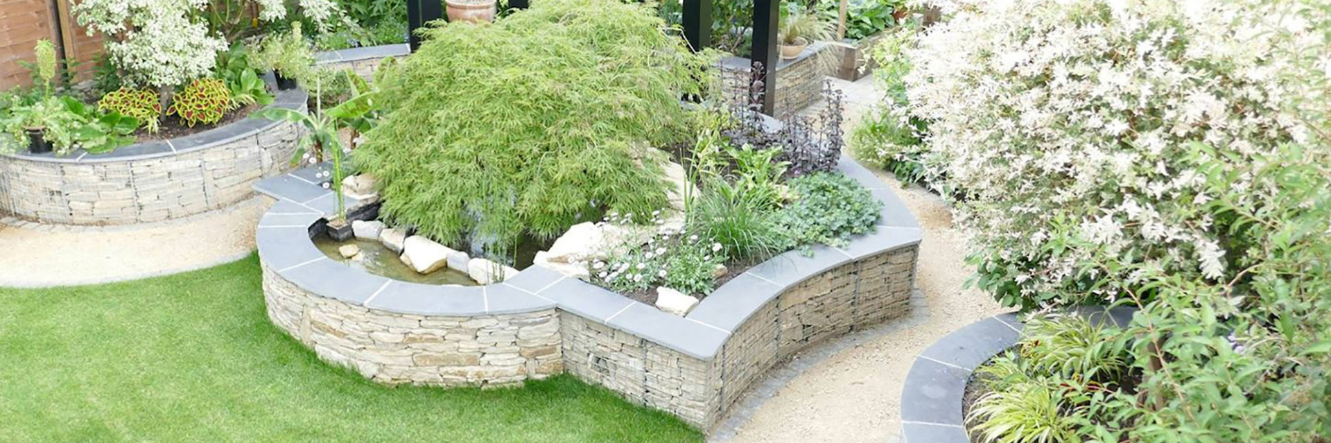 Garden design in St Albans, Hertfordshire with gabion retaining walls and a steel pergola.
